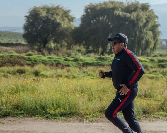 A man in sportswear jogging on a scenic rural path during the day.